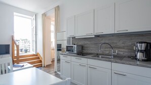 A modern kitchen with white cabinets, a built-in microwave, a coffee maker, and a sink. - 24-08 - resort Villa Apt 24-08. (Kühlungsborn)