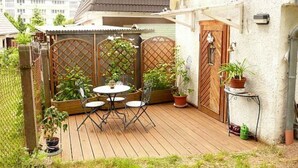 A wooden deck with a round table and chairs, surrounded by potted plants and a wooden fence. - Apartment 1 - Rügen-Fewo 249 (Sellin)