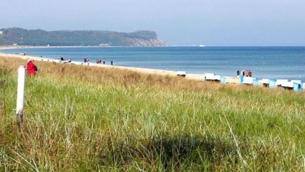 A beach with a grassy foreground, a sandy beach, and a distant landmass. - Apartment 1 - Rügen-Fewo 249 (Sellin)