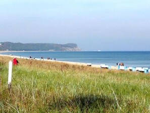 A beach with a grassy foreground, a sandy beach, and a distant landmass. - Apartment 1 - Rügen-Fewo 249 (Sellin)