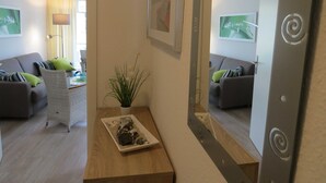 Uma sala de estar moderna com sofá, poltrona e uma mesinha com planta e objetos decorativos.