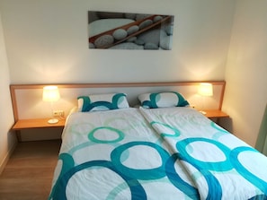 A neatly made bed with a patterned bedspread, two bedside lamps, and a framed picture on the wall.