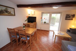 A living room with a wooden dining table, chairs, a television, and a sofa.