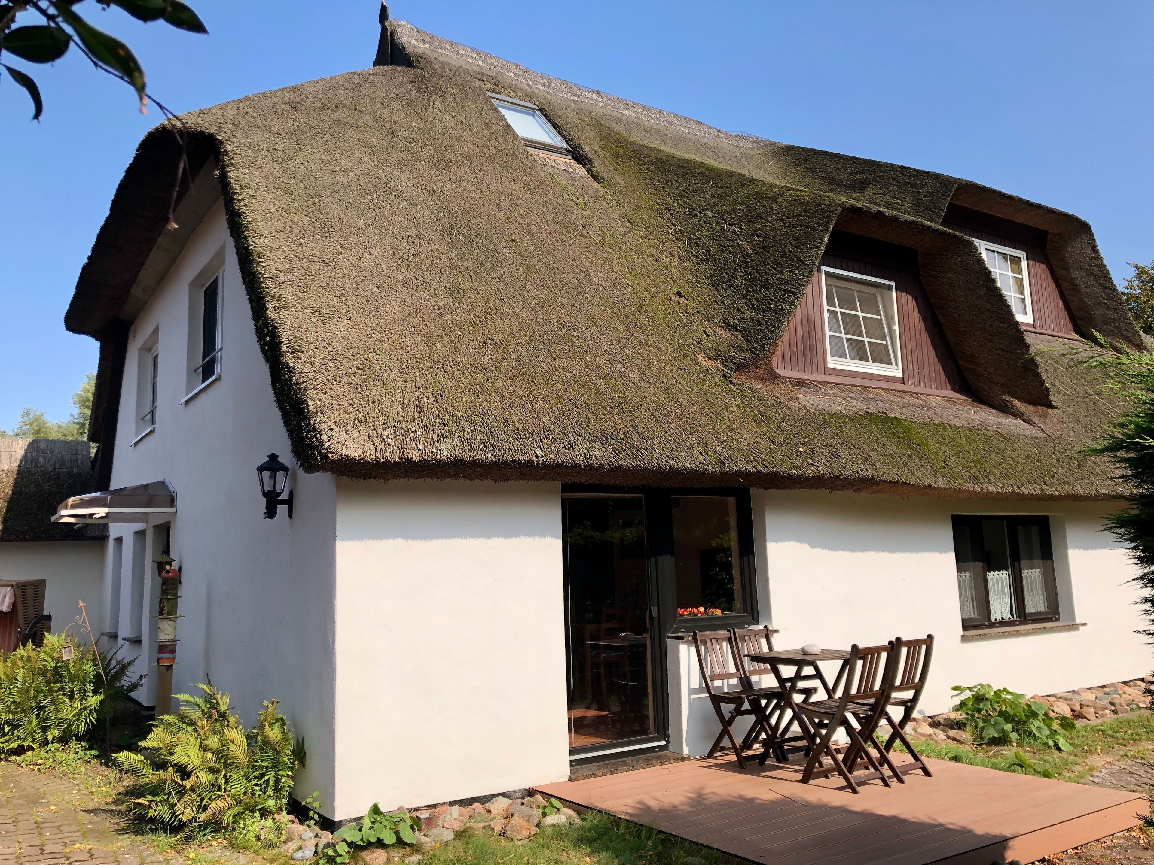 A traditional house with a thatched roof, a wooden door, and a small outdoor seating area.
