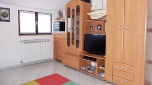 A room with a wooden cabinet, a television, and a sailboat model. - Holiday apartment with air conditioning and Internet (Medulin)