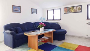 A living room with a blue sofa, a small wooden coffee table, and a colorful rug. - Holiday apartment with air conditioning and Internet (Medulin)