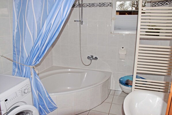 A bathroom with a bathtub, a toilet, and a washing machine.