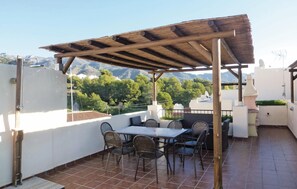 Eine Terrass mit Pergola, Tisch und Stühlen.