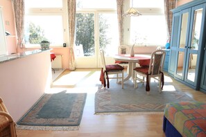 Un espace repas comprenant une table, des chaises et une vue à travers une porte vitrée.