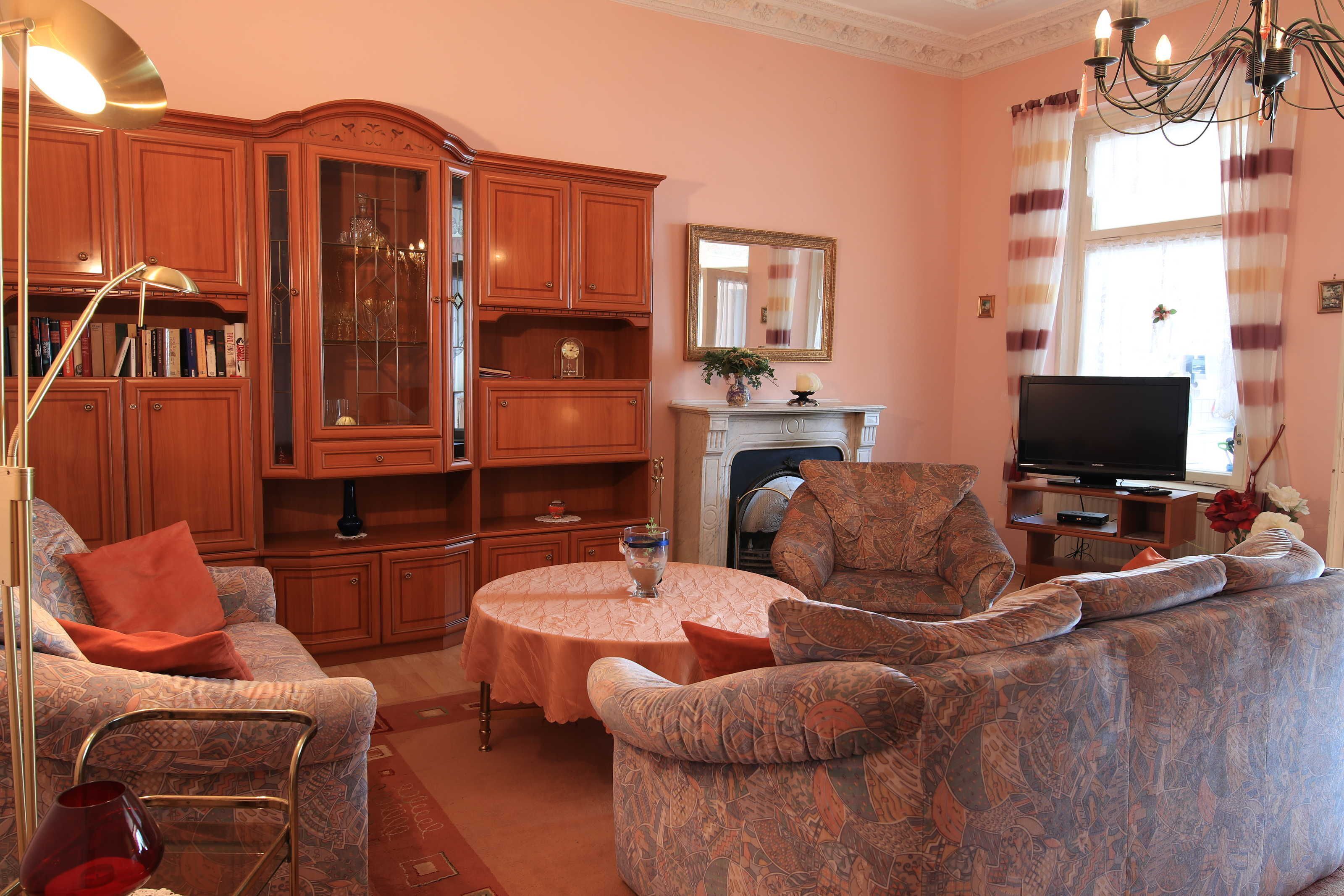 A living room with a fireplace, a television, and a large wooden cabinet.
