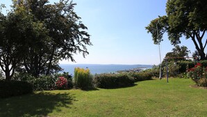 Zona verde con vista al mar, árboles y un arenero.