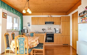 A compact kitchen with wooden cabinets, a microwave, a stove, and a dining area with chairs and a table.