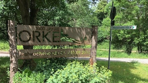 A wooden sign with text, surrounded by greenery and a road. - Ferienhof Döring - Apartment Döring (Vöhl)