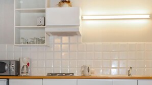 A kitchen with white cabinets, a microwave, a coffee maker, and a kettle on the counter. - Cozy apartment in Diksmuide with WiFi (Diksmuide)