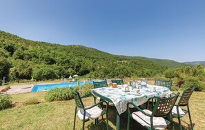 A poolside dining area with a table set for four, surrounded by chairs, overlooking a pool and lush greenery. - Lovely apartment in S.Vito In Monte TR (S.Vito In Monte TR)