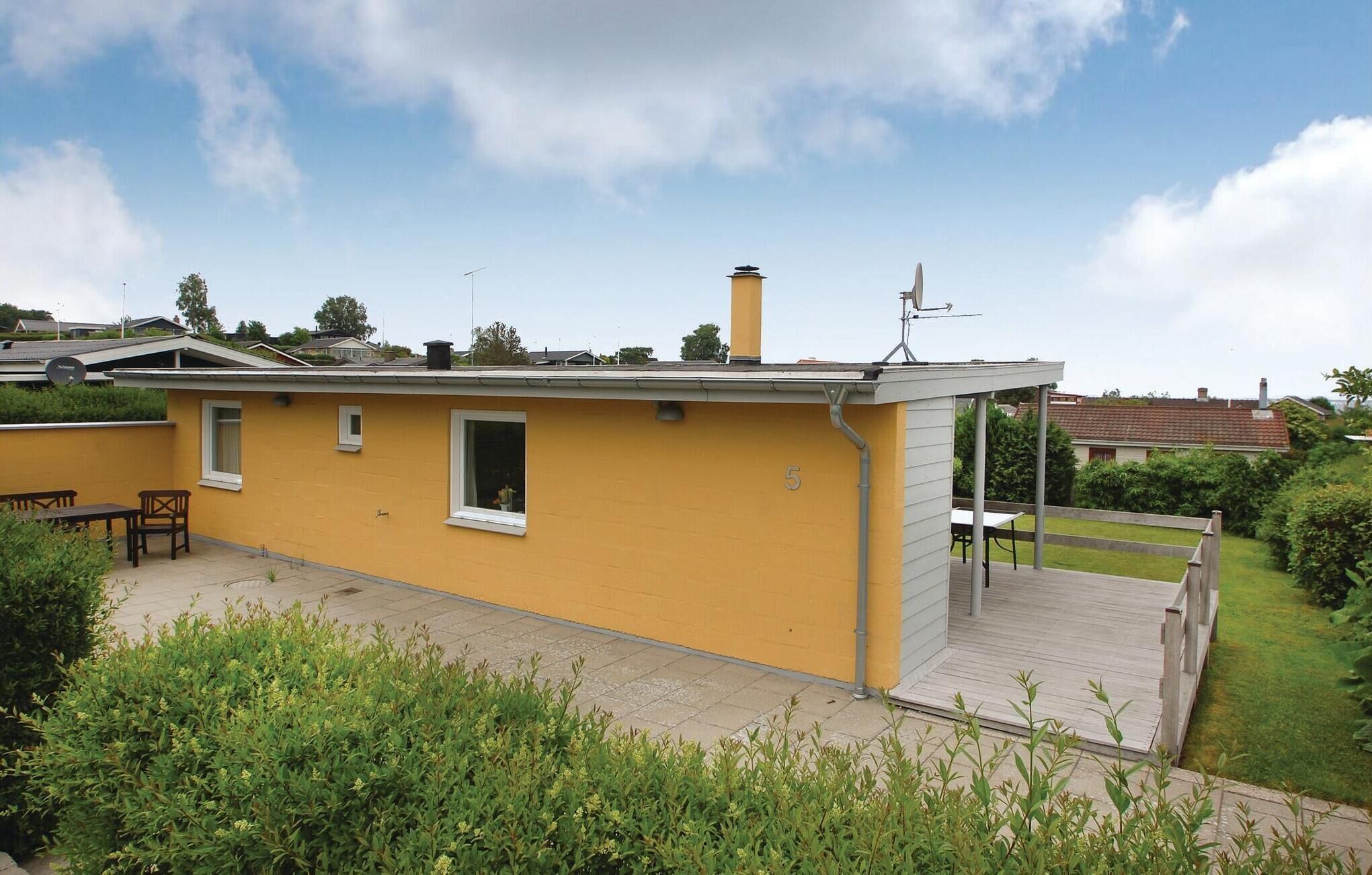 Ein gelbes Haus mit kleiner Terrasse und Schornstein.