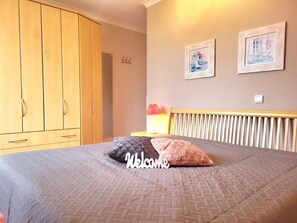 A bedroom with a bed, a wardrobe, and two framed pictures on the wall. - (190) 3-room apartment lake view - Apartment house Baltic Sea beach (Kühlungsborn)