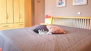 A bedroom with a bed, a wardrobe, and two framed pictures on the wall.
