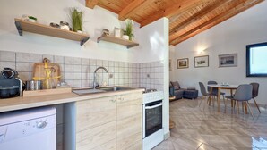Cozinha moderna com vigas de madeira, fogão embutido e área de jantar com mesa e cadeiras.