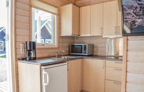 A compact kitchen with wooden cabinets, a stainless steel microwave, a coffee maker, and a sink. - Stunning home in Thyborøn with WiFi (Thyborøn)