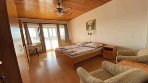 Una camera da letto con soffitto in legno, un letto con copriletto colorato, una sedia, un comodino e un quadro appeso al muro.
