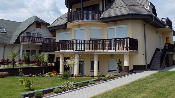 Una casa a due piani con un balcone, un camino e un giardino curato.