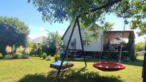 A backyard with a swing set, trampoline, and a house in the background. - Holiday home in a quiet location with terrace (Agárd)