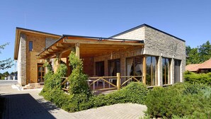 A modern building with a wooden facade, large windows, and a covered outdoor area. - Holiday home in a quiet location with terrace (Agárd)