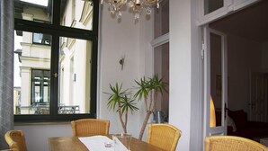 A dining area with a wooden table, wicker chairs, two potted plants, and a chandelier.
