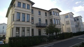 A multi-story building with a symmetrical facade, large windows, and a central balcony.