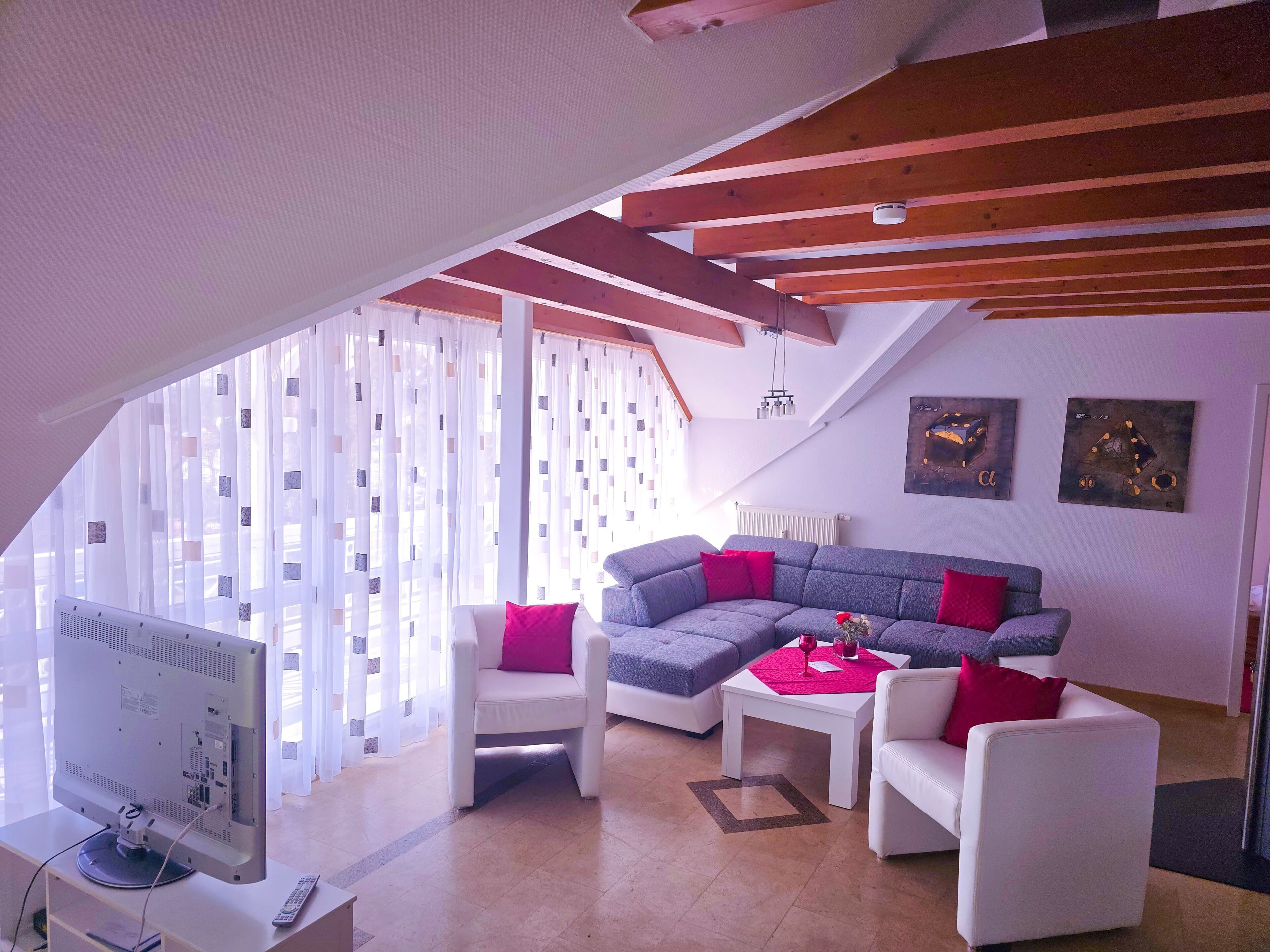 A modern living room with a sectional sofa, white armchairs, and a coffee table.