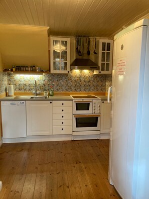 Una cocina con armarios de madera, horno integrado, lavavajillas y refrigerador.
