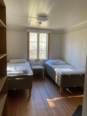 Una habitación con dos camas individuales, una mesita, una ventana y una lámpara en el techo.