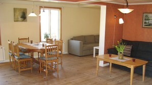 Et spiseområde med et træbord og stole, en sofa og et lille bord med en vase.