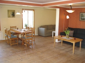 Et spiseområde med et træbord og stole, en sofa og et lille bord med en vase.