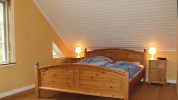 Une chambre à coucher avec un lit en bois, deux tables de chevet avec des lampes, une fenêtre et un plafond en pente.