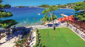 Une vue sur la côte, avec une eau claire, des bateaux et une plage aménagée avec des parasols et des sièges.