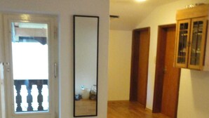 A spacious room with wooden flooring, a door leading to a balcony, and a large mirror on the wall.