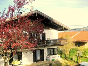 A two-story house with a balcony, a satellite dish, and a garden.