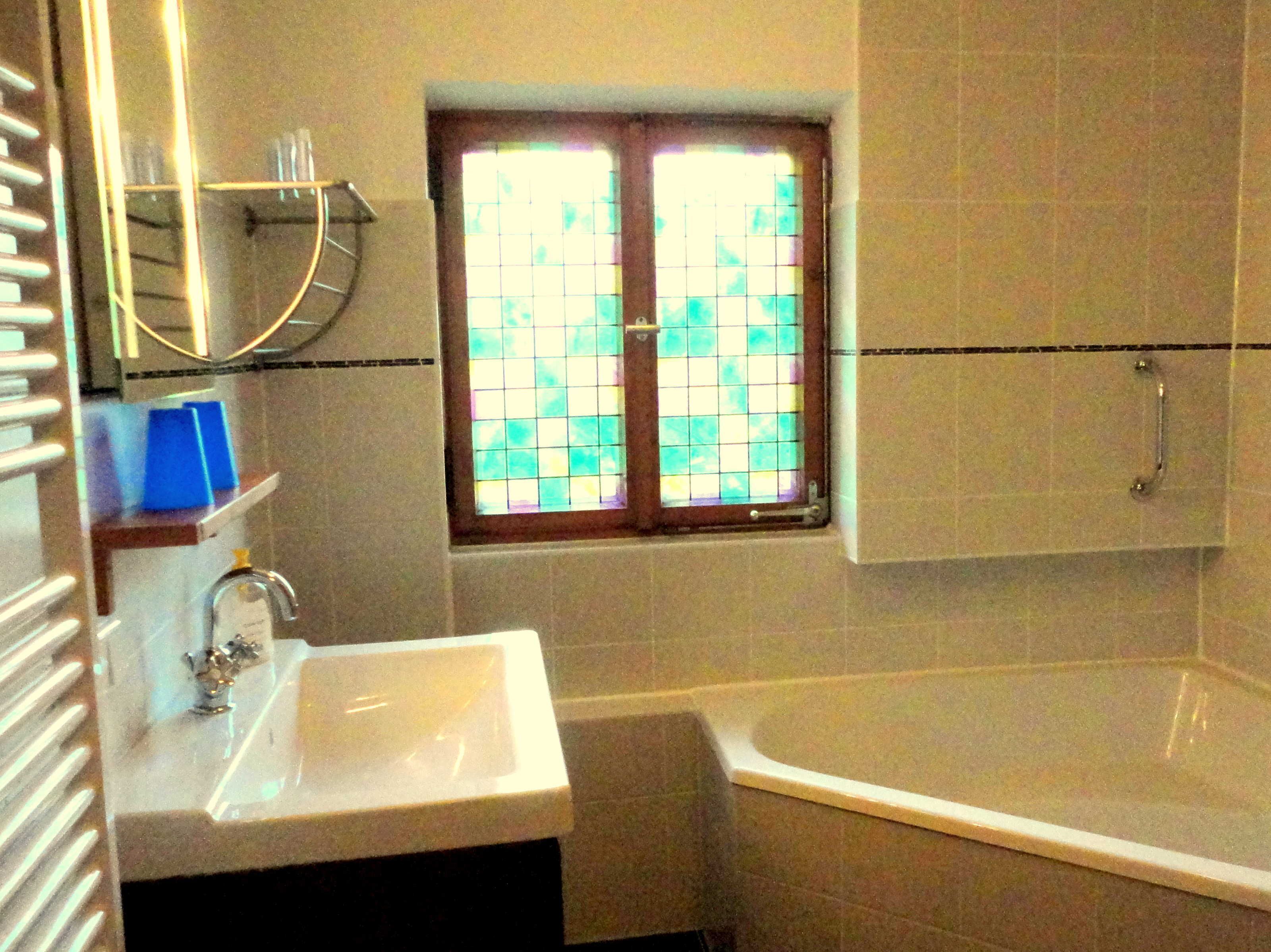 A bathroom with a white sink, a bathtub, and a window with a grid pattern.