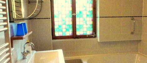A bathroom with a white sink, a bathtub, and a window with a grid pattern.
