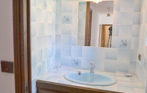 A bathroom with a blue sink, a mirror, and light blue tiles with floral patterns. - Beautiful home in Clohars Carnoet (Clohars Carnoet)