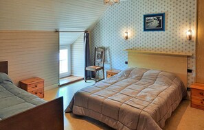 A bedroom with a large bed, a chair, a nightstand, a dresser, a window, and a wall-mounted picture. - Beautiful home in Clohars Carnoet (Clohars Carnoet)