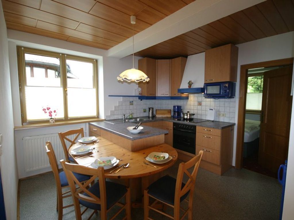 Une cuisine avec des meubles en bois, une table à manger avec des chaises, un four à micro-ondes et une fenêtre donnant sur un beau paysage.
