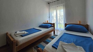 A bedroom with two single beds, a window with sheer curtains, and a view of greenery outside. - Holiday apartment with air conditioning and barbecue (Medulin)