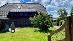 Ein Ziegelhaus mit geneigtem Dach, einem Holzzaun und einem Rasen.