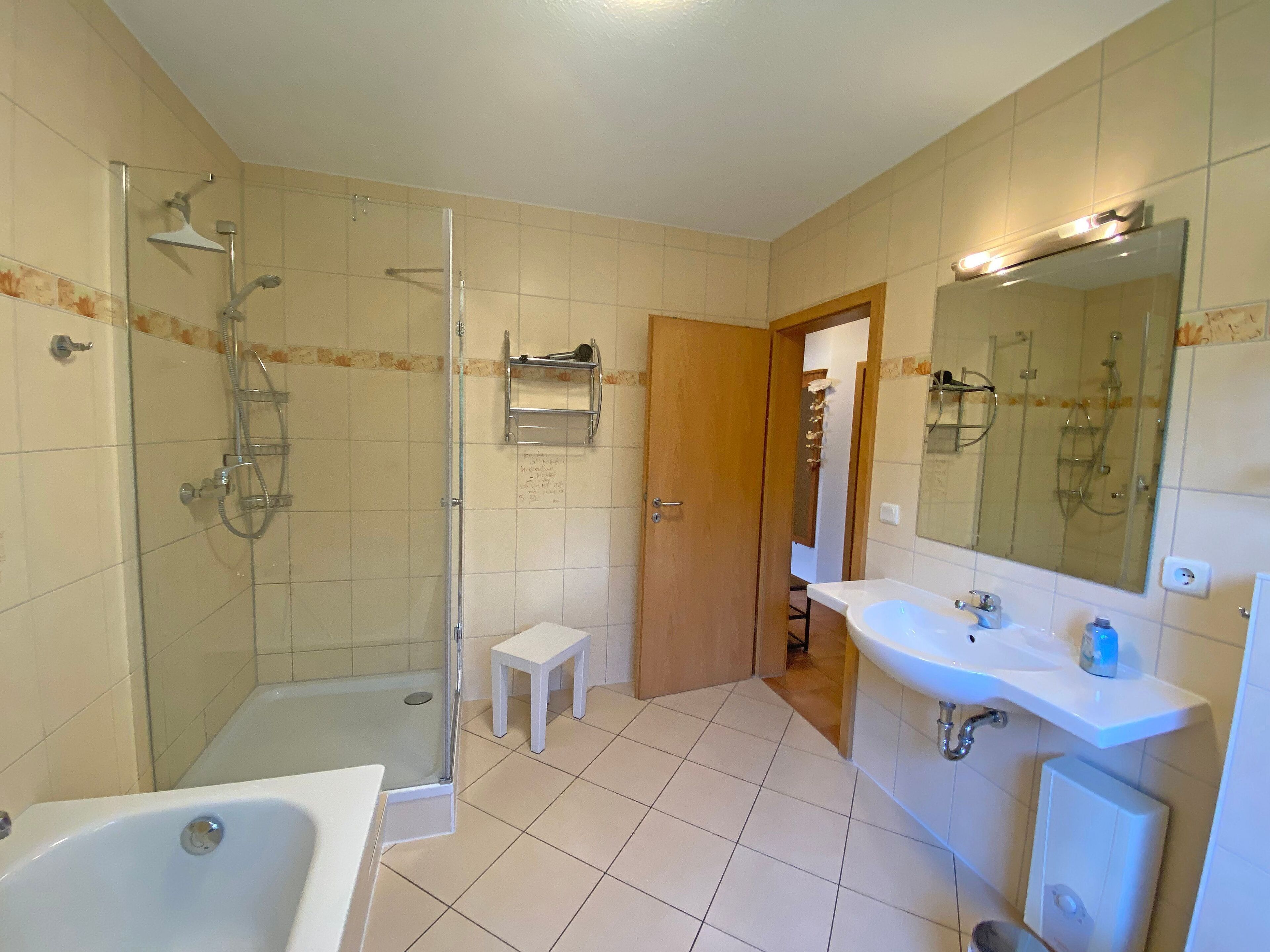 A bathroom with a shower, a bathtub, a sink, and a mirror.