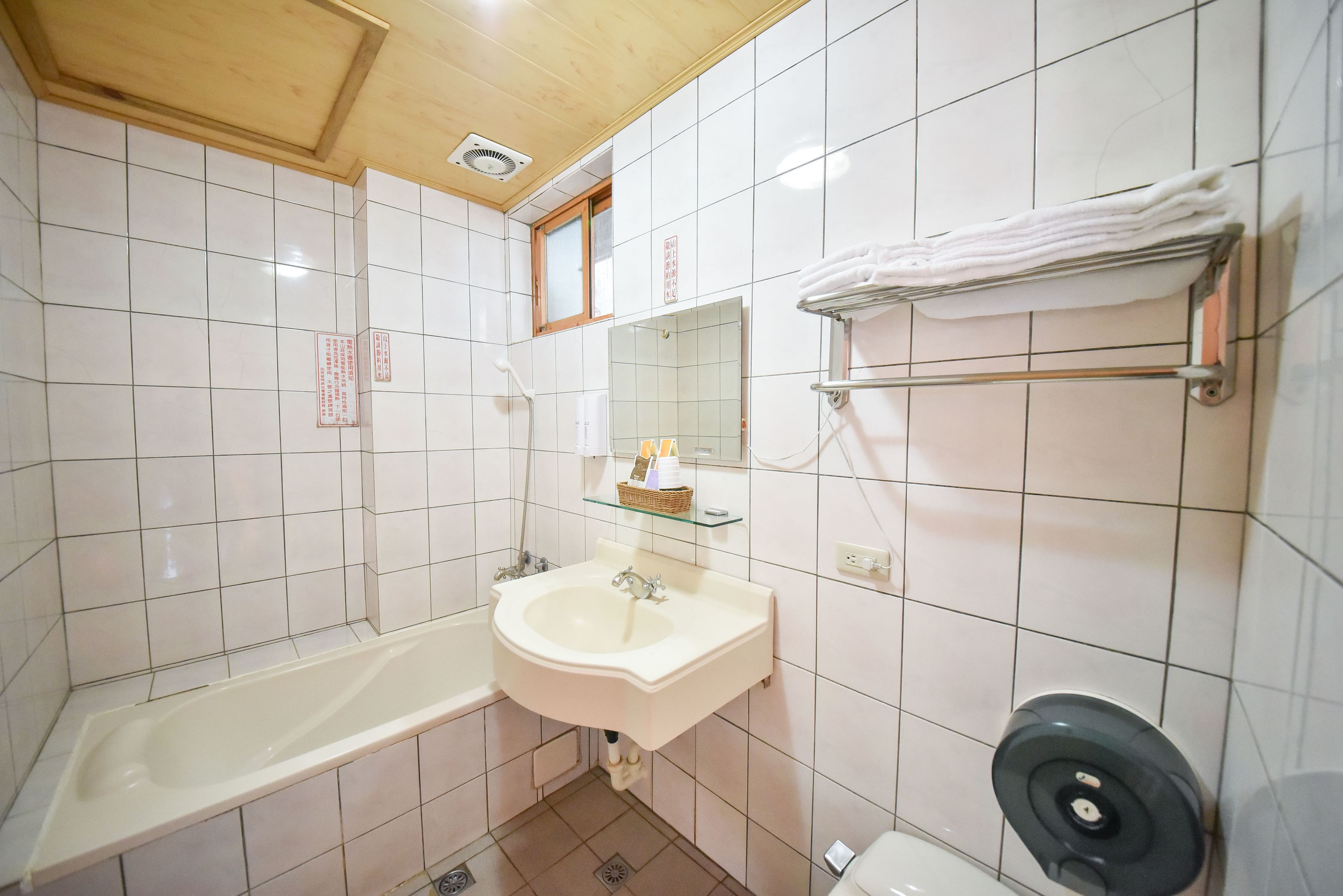 A bathroom with white tiles, a sink, a bathtub, a towel rack, and a toilet.