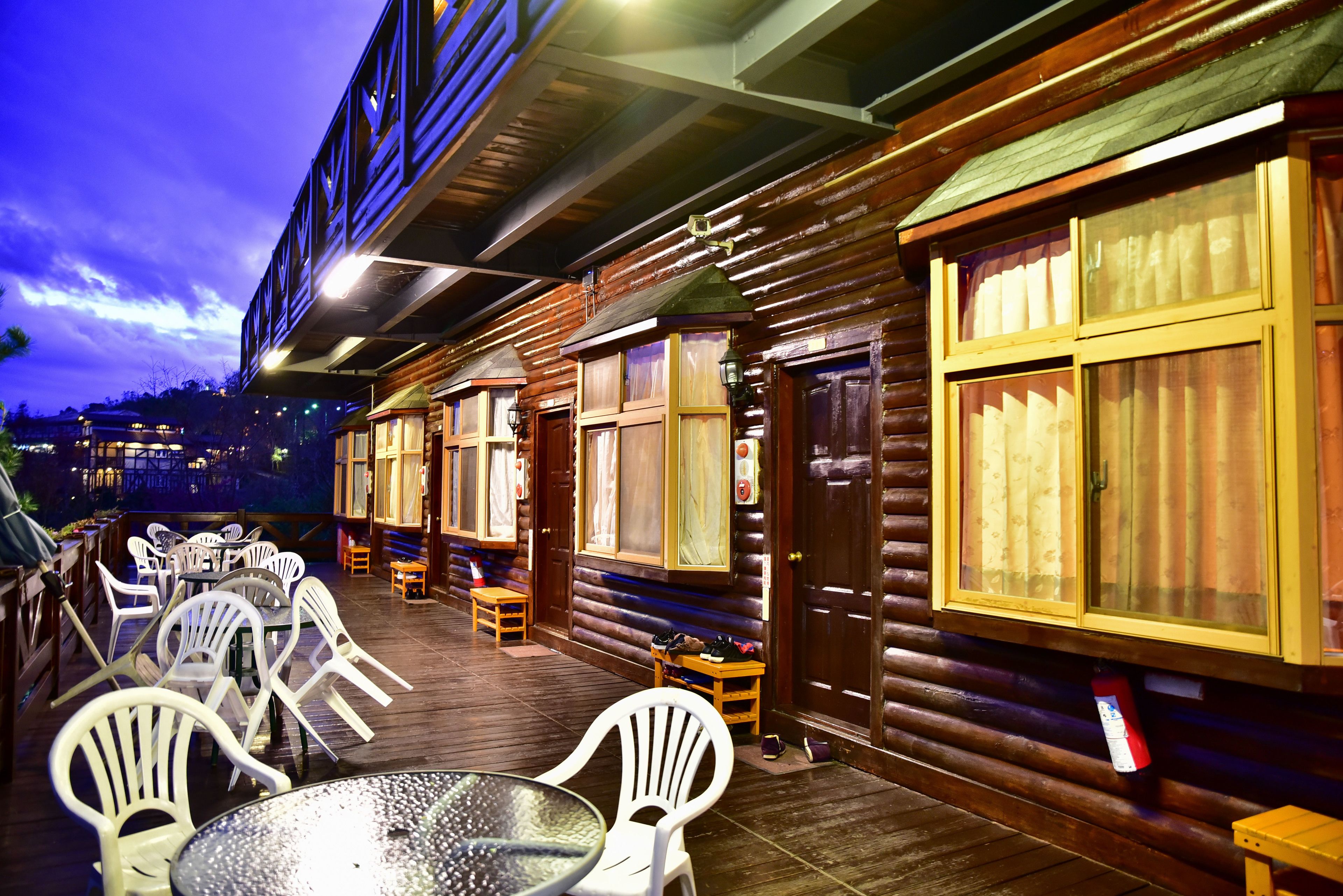 A wooden cabin-style building with a covered patio area featuring tables and chairs.