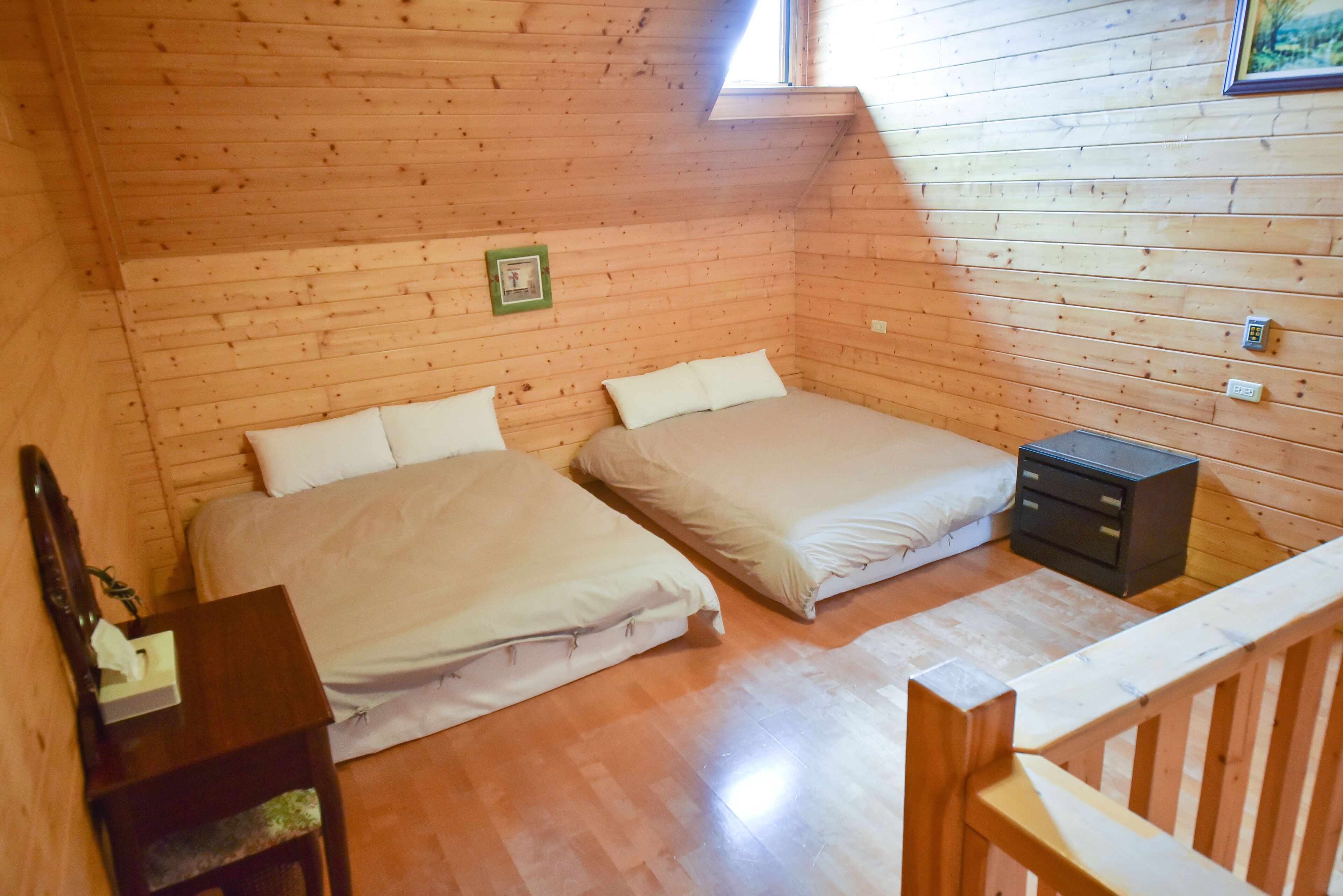 Una habitación pequeña y acogedora con dos camas, paredes de madera, una mesita y una ventana.